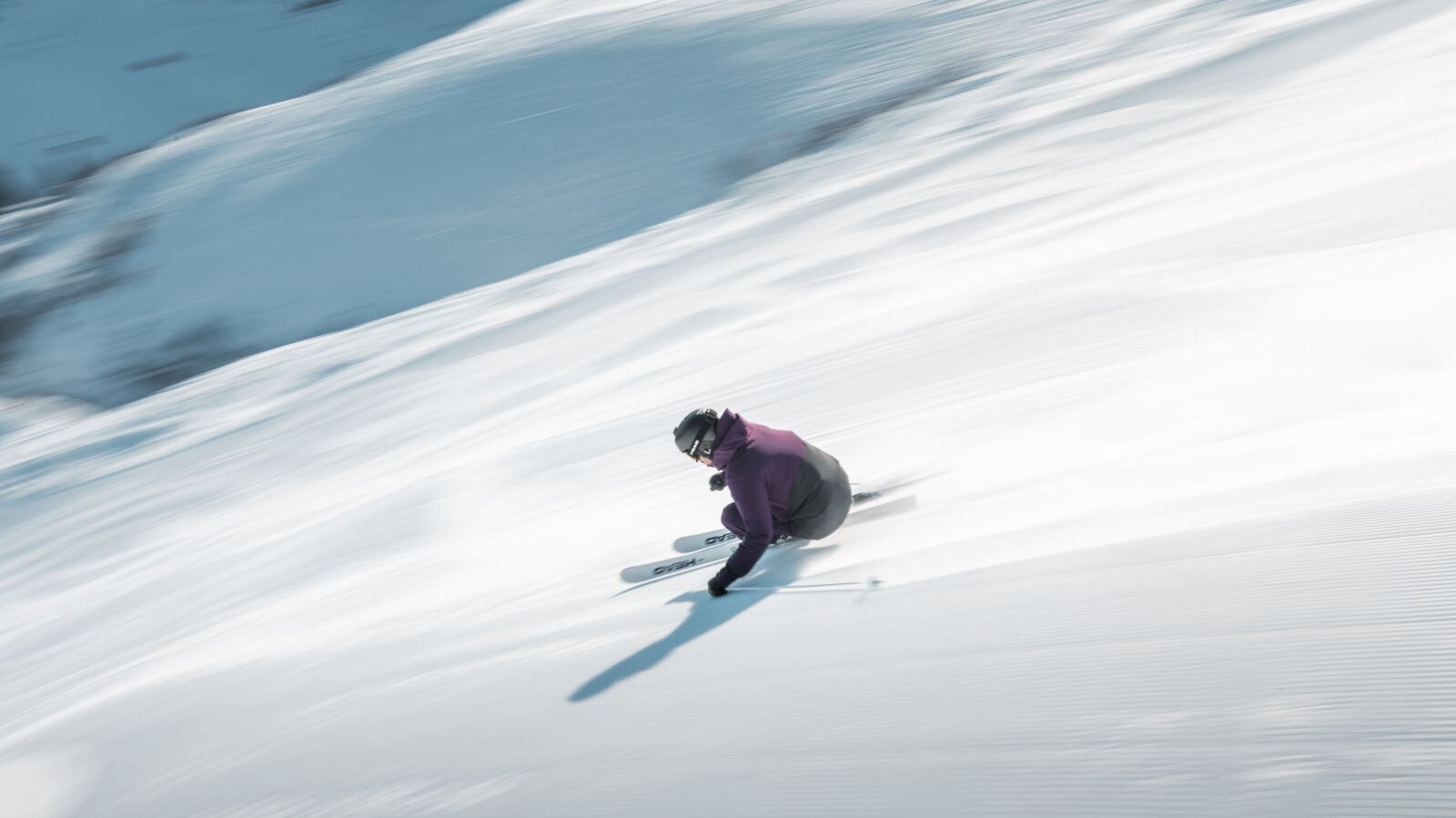 Skifahrer in Bewegung auf einer verschneiten Piste mit winterlicher Landschaft im Hintergrund