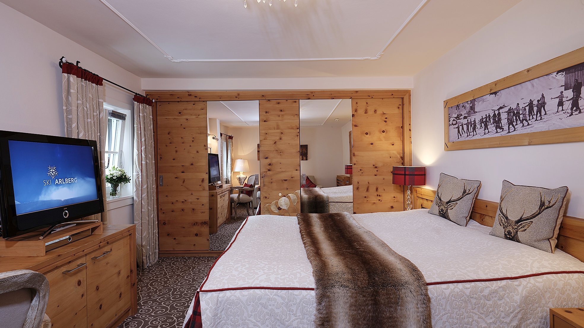 Doppelzimmer Luxuriöse Hotelunterkunft mit großem Bett und Holzmöbeln im Alpenstil ohne sichtbare Personen.