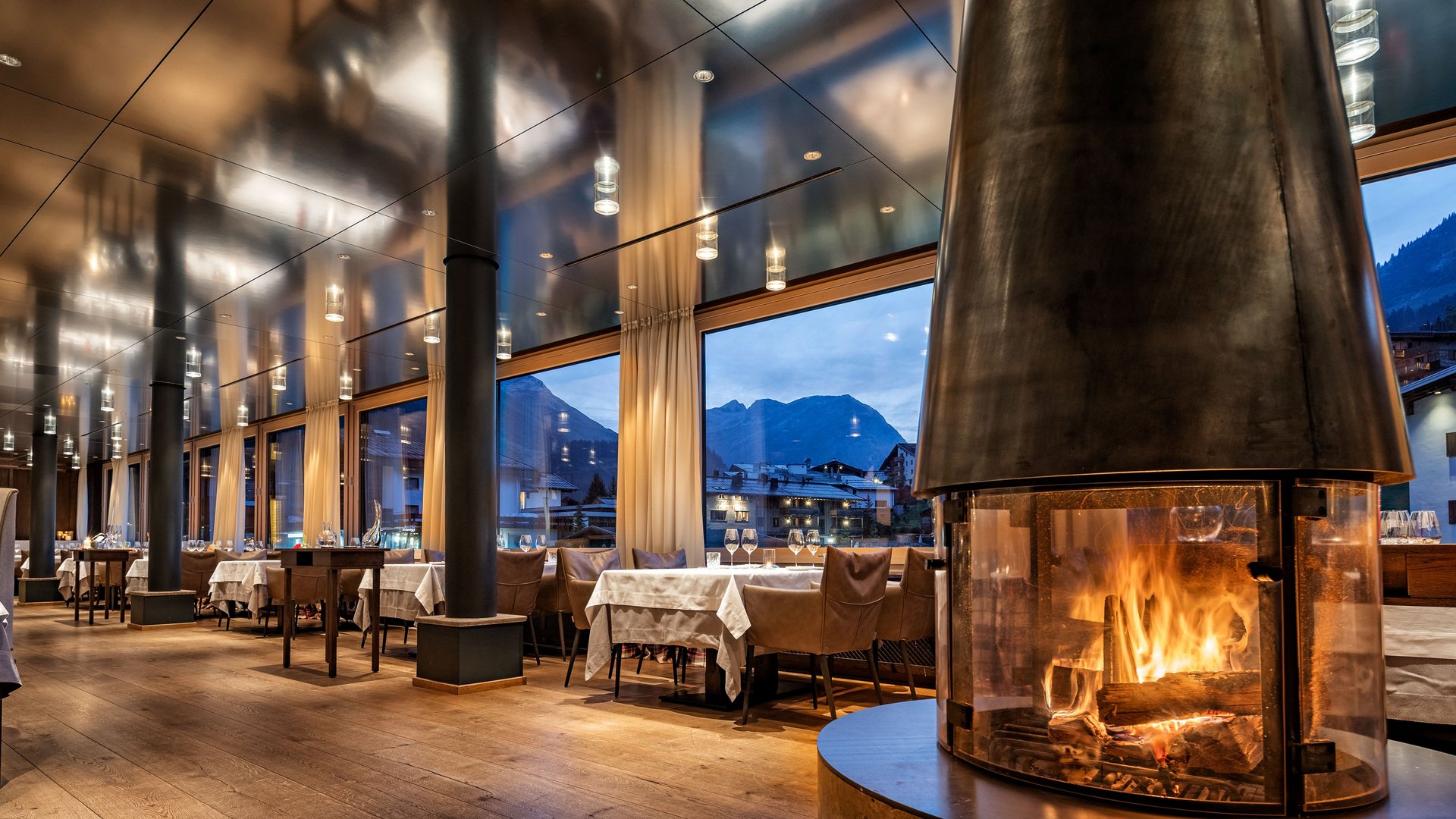 Das Panoramarestaurant im Krone Lech in modernem Stil und einem Glas Kamin in der Mitte