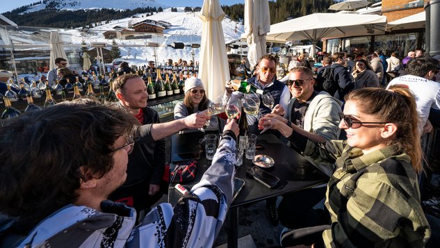Anstoßen mit Getränken auf der Skihütte.
