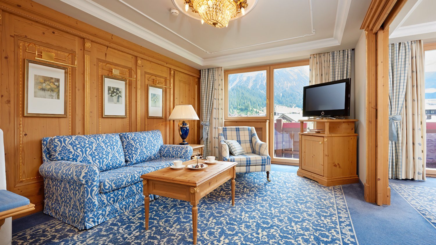 Junior Suite Hochwertiges Hotelzimmer mit Holzverkleidung und eleganter Einrichtung sowie großen Fenstern zur Berglandschaft