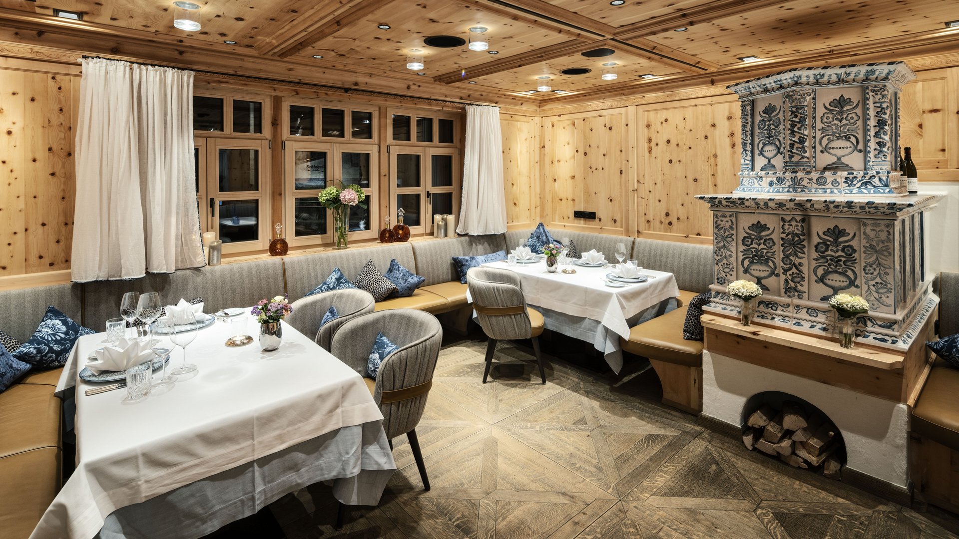 Elegant parlor with wooden walls, tiled stove and lovingly laid tables.