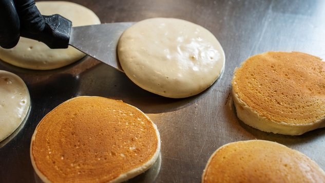 Frische Pancakes werden auf einer heißen Platte zubereitet.