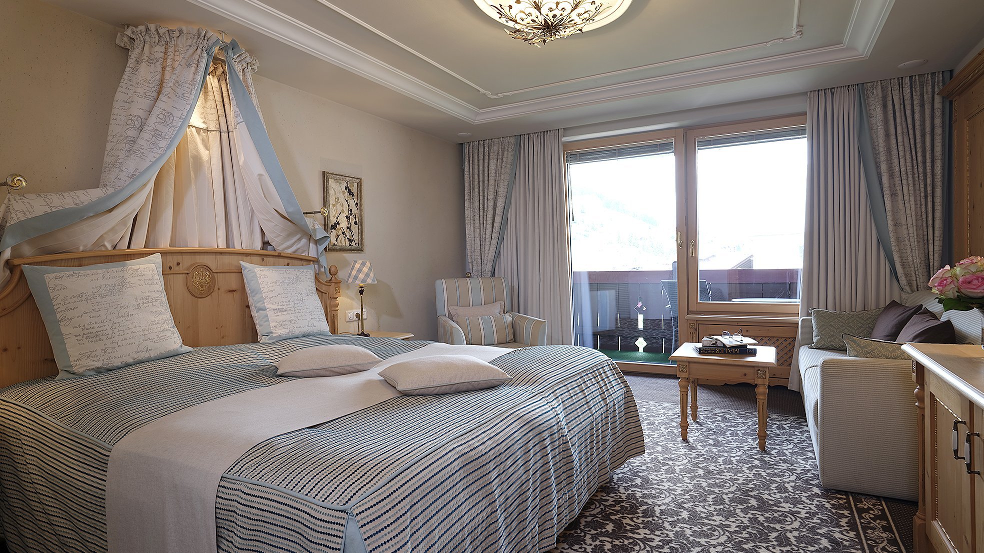 Doppelzimmer Deluxe Hotelzimmer mit großem Bett, Sitzbereich und Fenstern für viel Tageslicht. Modernes Interieur.