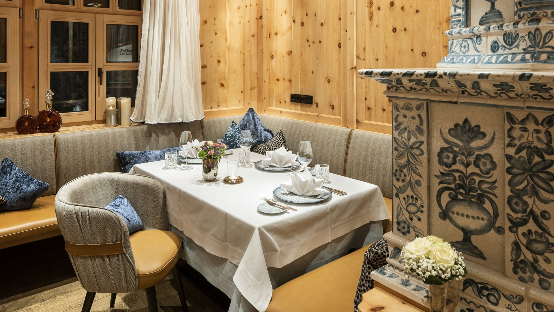 Cozy parlor with wooden walls, stove and elegantly laid table.