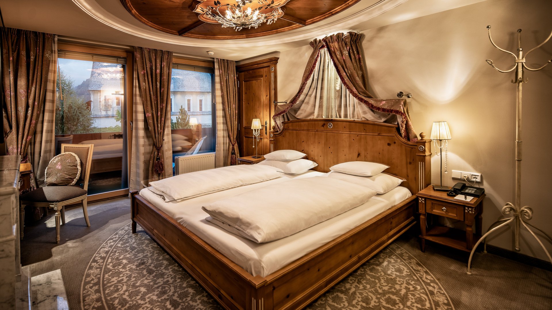 Furnished hotel room featuring a wooden bed and decorative elements on the ceiling.