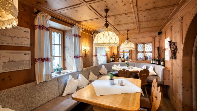 Gemütliche Holzstube mit gedeckten Tischen und Sitzbänken in Lech am Arlberg.
